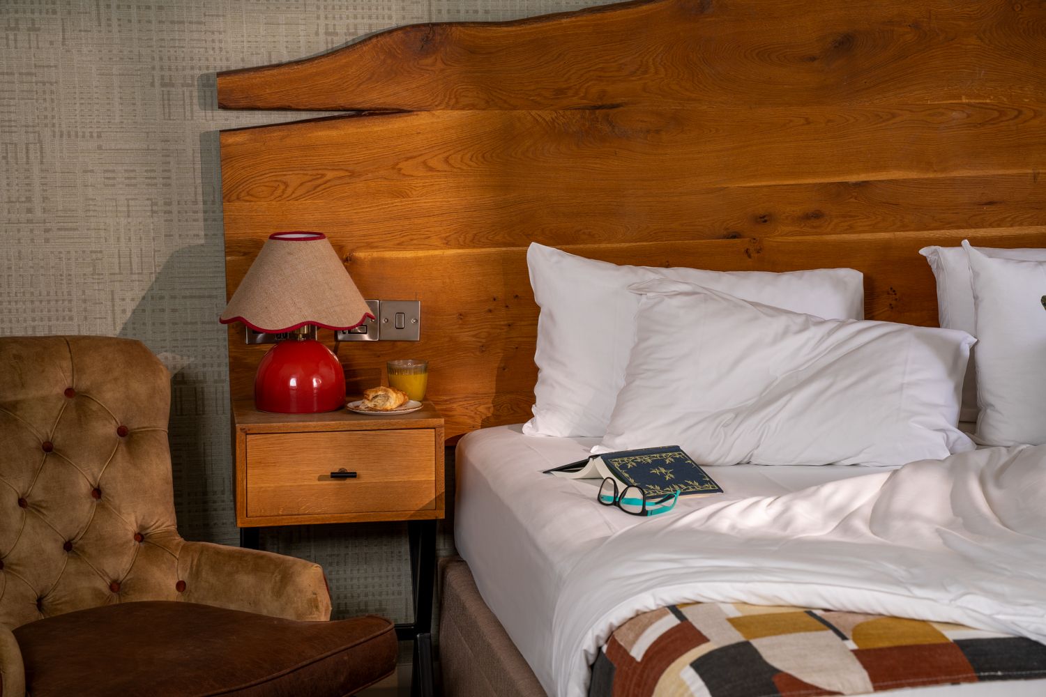 unmade bed in the feature room with a book and glasses